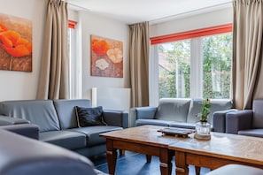 A modern living room with grey sofas, a wooden coffee table, and artwork on the walls. - Group Getaway in Arcen (Arcen)