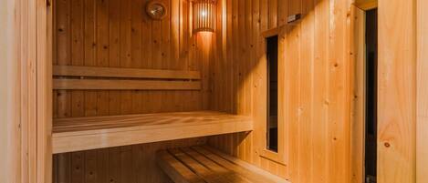A wooden sauna with a sloped ceiling, a bench, and a wall-mounted clock.