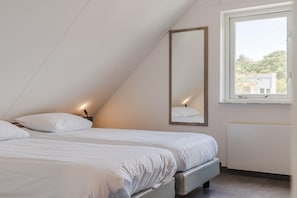 A bedroom with two beds, a large mirror, and a window.