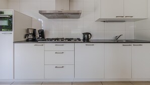 A modern kitchen with white cabinetry, a stainless steel range hood, a coffee maker, and a kettle. - Villa in Arcen with Private Pool & Wellness (Arcen)