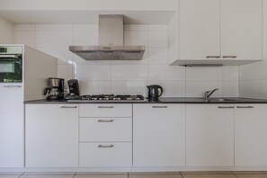 A modern kitchen with white cabinetry, a stainless steel range hood, a coffee maker, and a kettle. - Villa in Arcen with Private Pool & Wellness (Arcen)