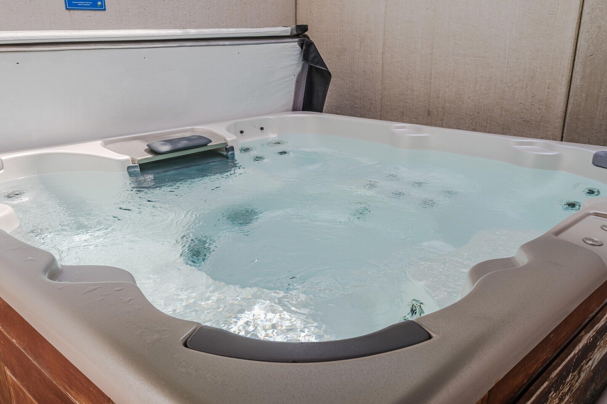 Ein Whirlpool mit integriertem Sitz und Massagedüsen vor einer schlichten Wand.