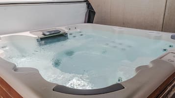 A hot tub with a built-in seat and jets, set against a plain wall.