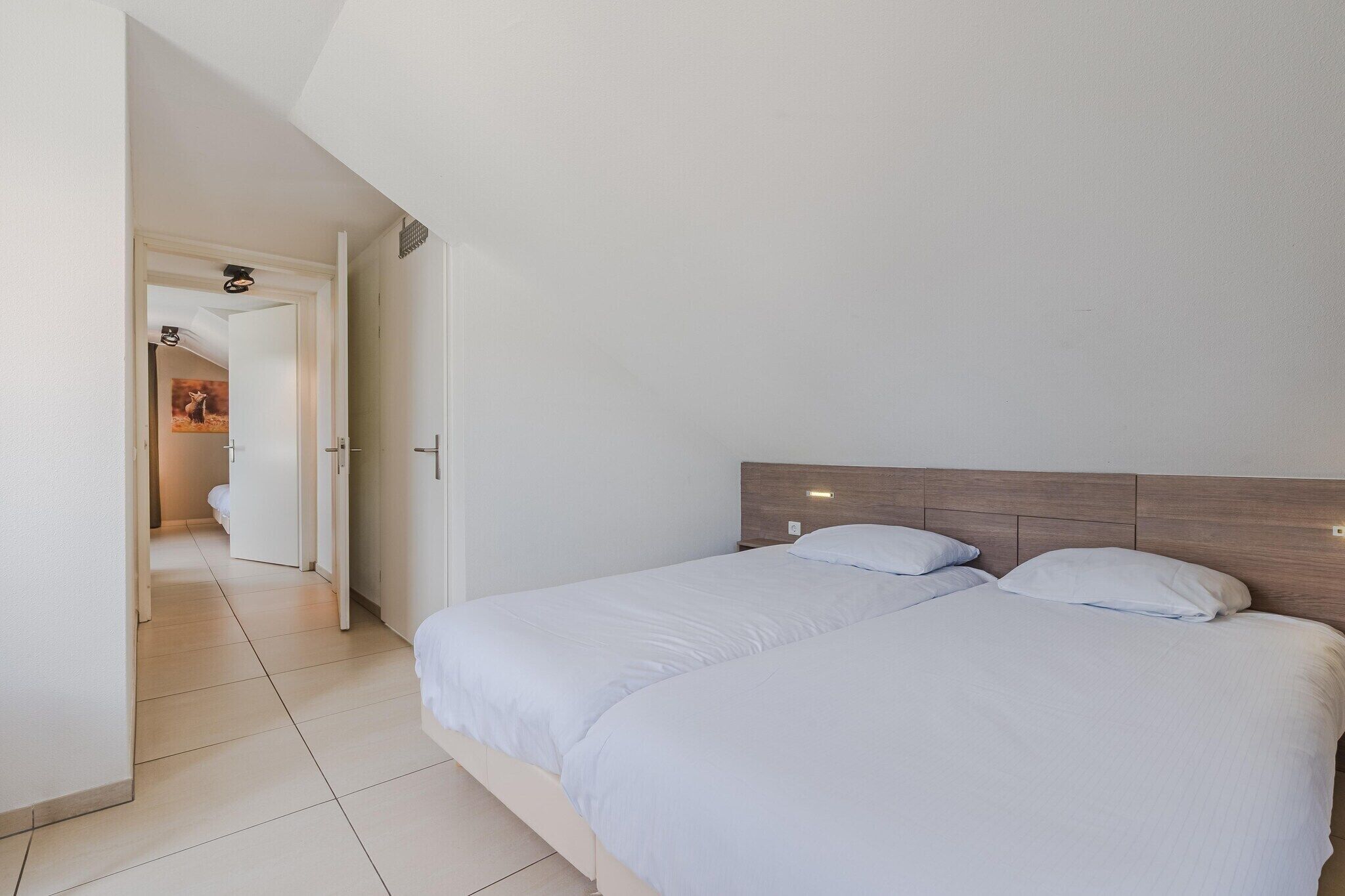 Een hotelkamer met een groot bed, een houten hoofdbord en een betegelde vloer.