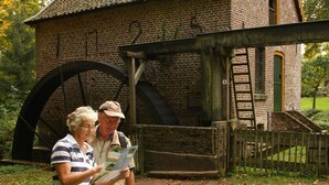 A historic building with a large water wheel, brick walls, and a wooden fence. - Holiday Home in Netherlands with Private Garden (Plasmolen)