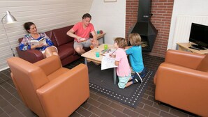 Un salon chaleureux avec des canapés en cuir, une cheminée en briques et un téléviseur.
