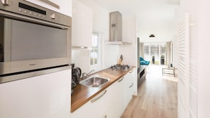 A modern kitchen with a stainless steel stove, a wooden countertop, and white cabinetry. - Stylish Woodland Chalet (Hoge Hexel)