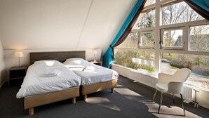 Une chambre avec deux lits, une chaise et une grande fenêtre avec des rideaux.