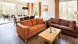 Una sala de estar moderna con dos sofás, una mesa de centro de madera y un comedor con sillas y una mesa.
