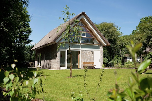 Ein Haus mit geneigtem Dach, einer Veranda und einem kleinen Garten.