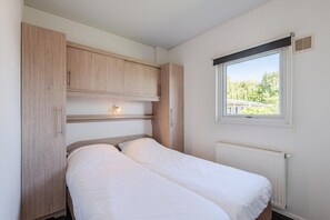 Ein Schlafzimmer mit einem Bett, einem Holzschrank und einem Fenster mit Blick.