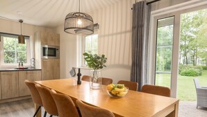 A modern kitchen with wooden cabinets, a built-in microwave, and a large window. - Thatched Villa in National Park (Paasloo)