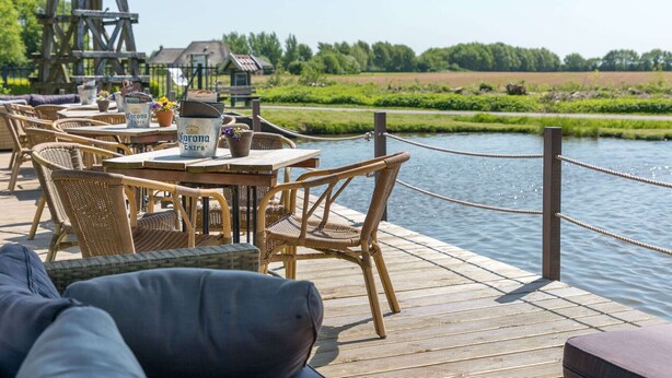 A wooden deck with wicker furniture and a view of a river.