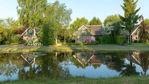 A serene lakeside property with a pond reflecting the surrounding trees and houses.