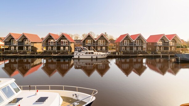 A row of traditional houses with red roofs along a calm waterway.