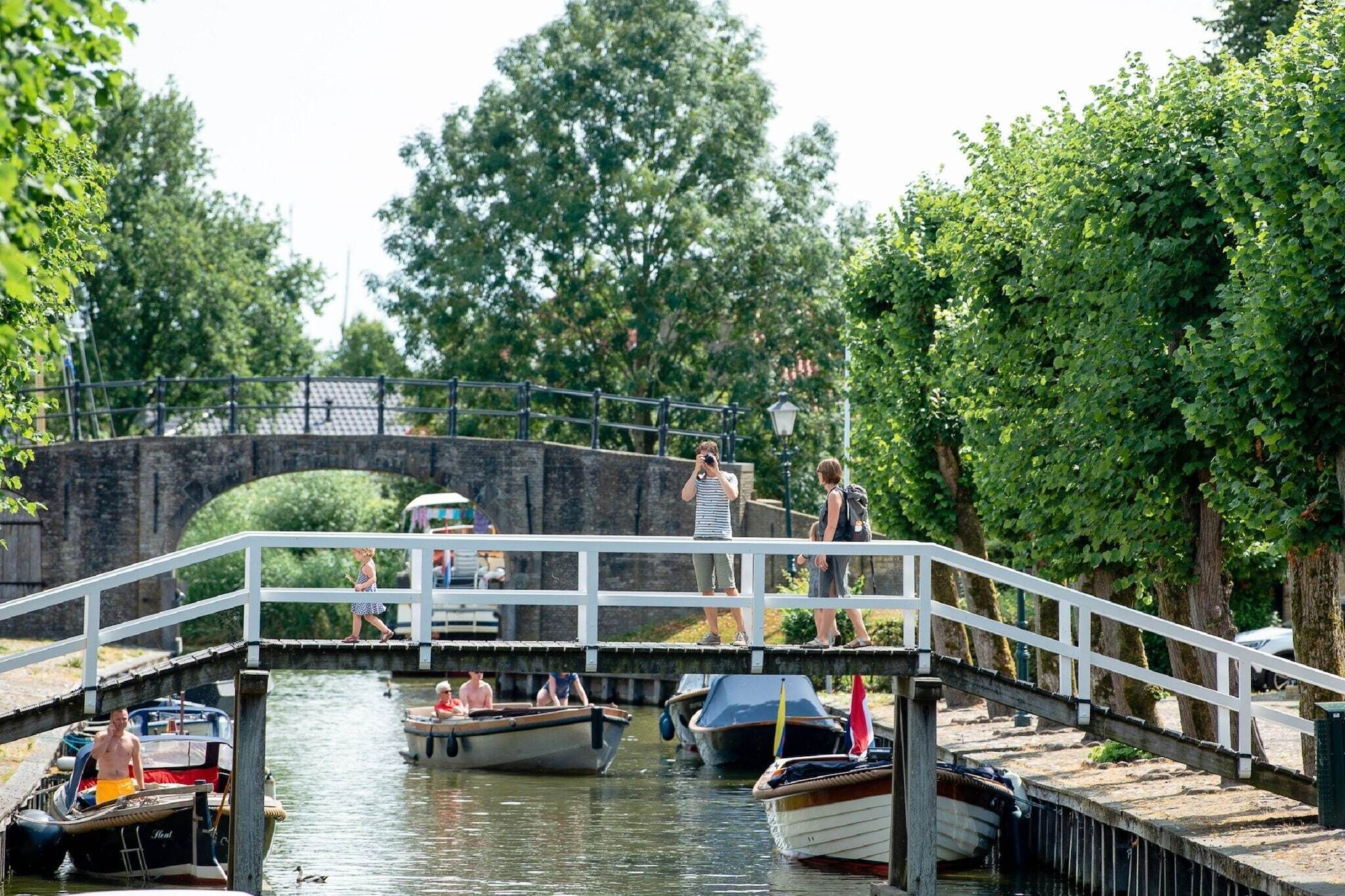 Eine Brücke über einen Kanal mit anlegenden Booten und Fußgängern.