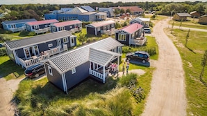 Zona residencial com várias casas, estrada de terra e paisagem gramada.