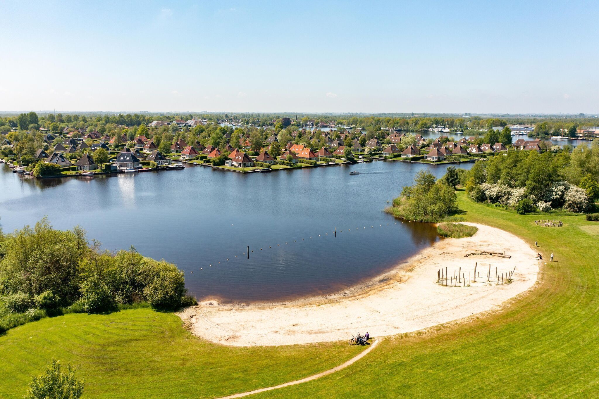 A lakeside residential area with houses, a sandy beach, and a boat dock.