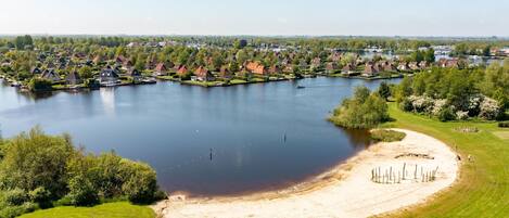 A lakeside residential area with houses, a sandy beach, and a boat dock.