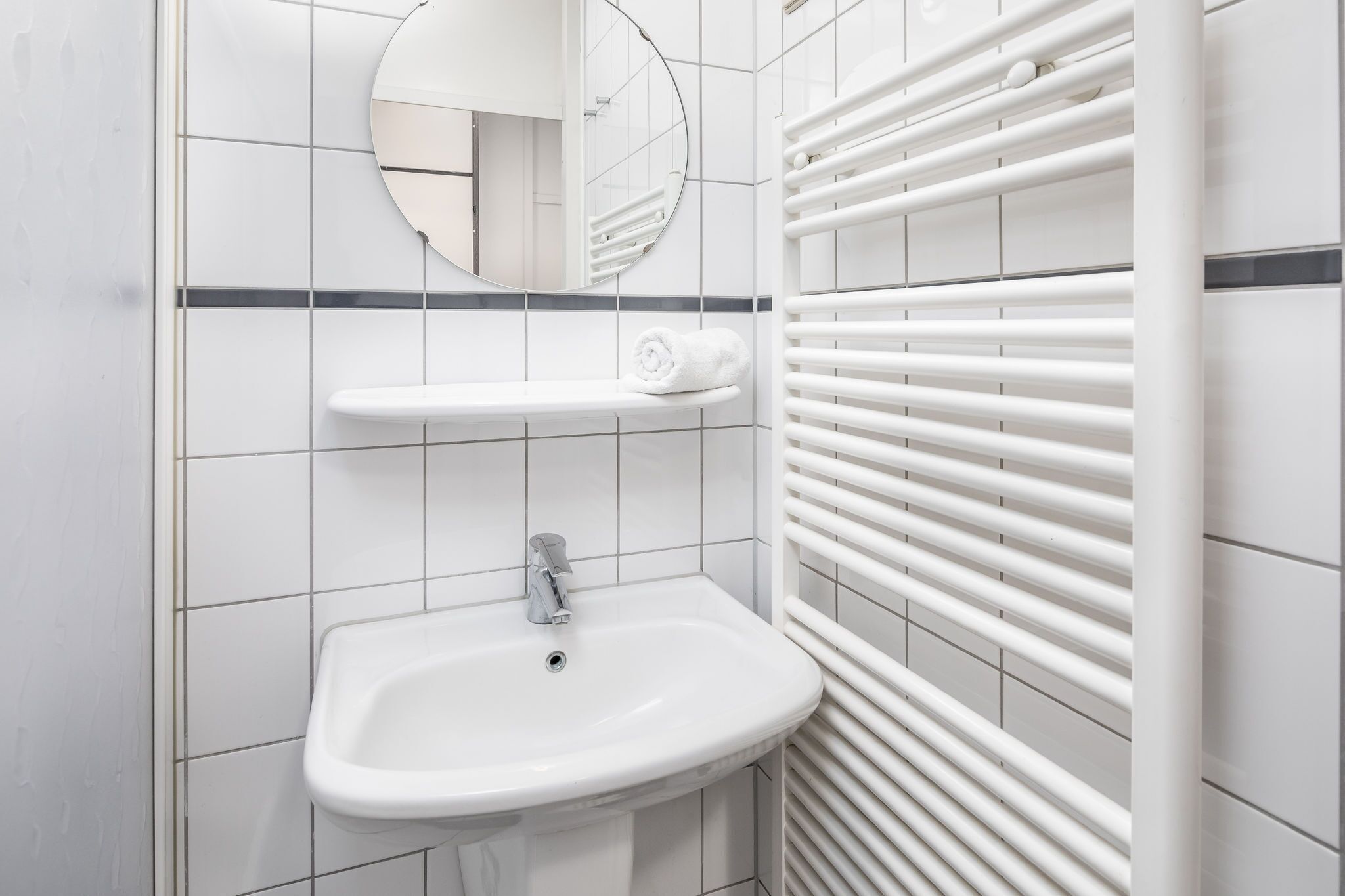 A bathroom with a white sink, a mirror, and a towel rack.