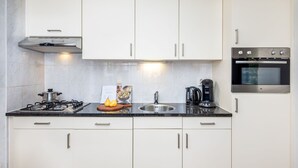 Eine moderne Küche mit weißen Schränken, einem Gasherd, einer Kaffeemaschine und einem Einbauofen.