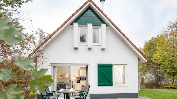 Ein zweistöckiges Haus mit weißer Fassade, grünen Fensterläden und einem Ziegeldach.