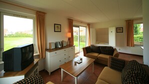 A living room with a television, sofa, and coffee table. There are curtains on the windows, and a picture frame on the wall. - Pet-friendly villa in Park Ankeveen (Tynaarlo)