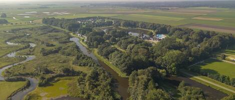 An aerial view of a rural landscape with a river, fields, and scattered buildings.
