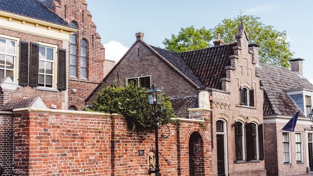 En historisk byggnad med en fasad av tegel, välvda fönster och ett traditionellt tak.