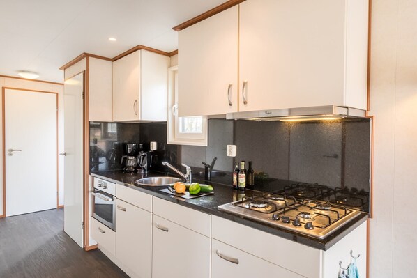 Una cocina moderna con armarios blancos, encimera negra, estufa y lavabo.
