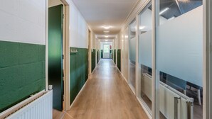 En lång, smal hall med trägolv och grönmålade väggar.