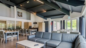 En modern hotellobby med en stor grå soffa, matbord och stolar.