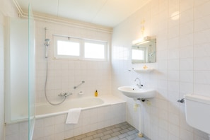 Une salle de bain moderne dotée d’une douche à parois de verre, d’une baignoire, d’un lavabo et de toilettes.