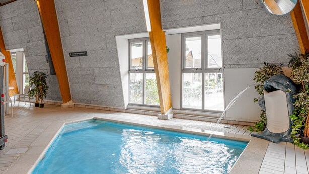 An indoor swimming pool with a clear view of the surrounding area, including a sign indicating the location and a view of the outside through large windows. - Forest Stay with Shared Pool (Borger)