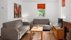 A modern living room with two sofas, a wooden coffee table, a television, and a window with a view of greenery. - Forest Stay with Shared Pool (Borger)