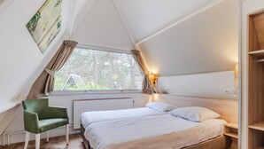 A bedroom with a bed, a chair, a window, and a shelf.