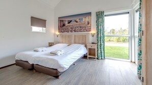 Un dormitorio con cama, una mesita de noche, un cuadro y vistas al exterior.