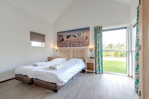Un dormitorio con cama, una mesita de noche, un cuadro y vistas al exterior.