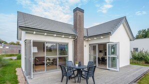 Una casa moderna con un patio, una chimenea y un ventanal corredera que da a una sala de estar.