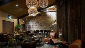 Un restaurante acogedor con paredes de madera, asientos de cuero y lámparas colgantes.