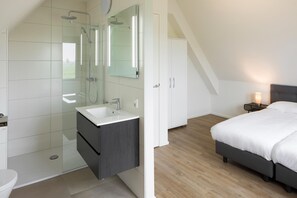 A modern bedroom with a bed, bedside table, and a nightstand with a lamp. - Luxury Villa on the Water (Ossenzijl)
