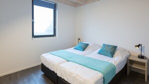 A bedroom with a large bed, two pillows, a bedside table with a lamp, and a window with blinds. - Vacation Stay Close to Tjeukermeer (Langelille)
