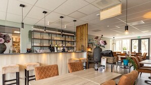 A modern restaurant with a bar area, wooden tables, and cushioned chairs. - Bungalow in Veluwe with Infrared Sauna (Putten)