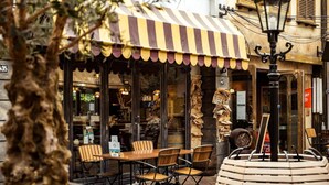 An outdoor café with striped awning, wooden tables, and chairs. - Designer Chalet in the Veluwe (Wissel/Epe)