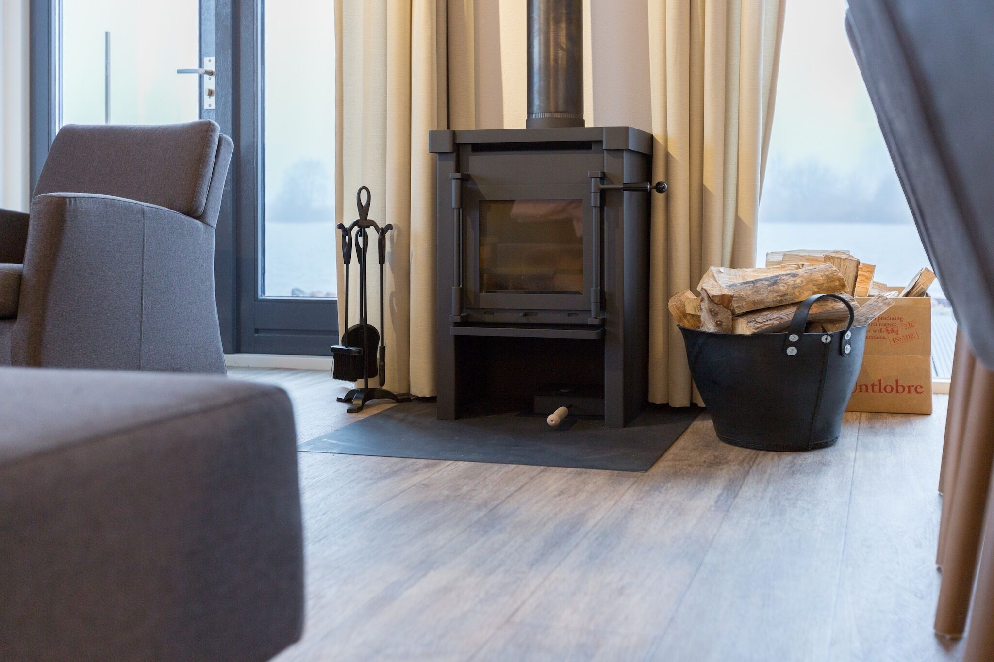 Een moderne woonkamer met een houtkachel, een comfortabele bank en uitzicht op de omgeving.