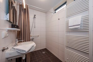 Ett litet badrum med handfat, toalett, dusch och handdukshängare.