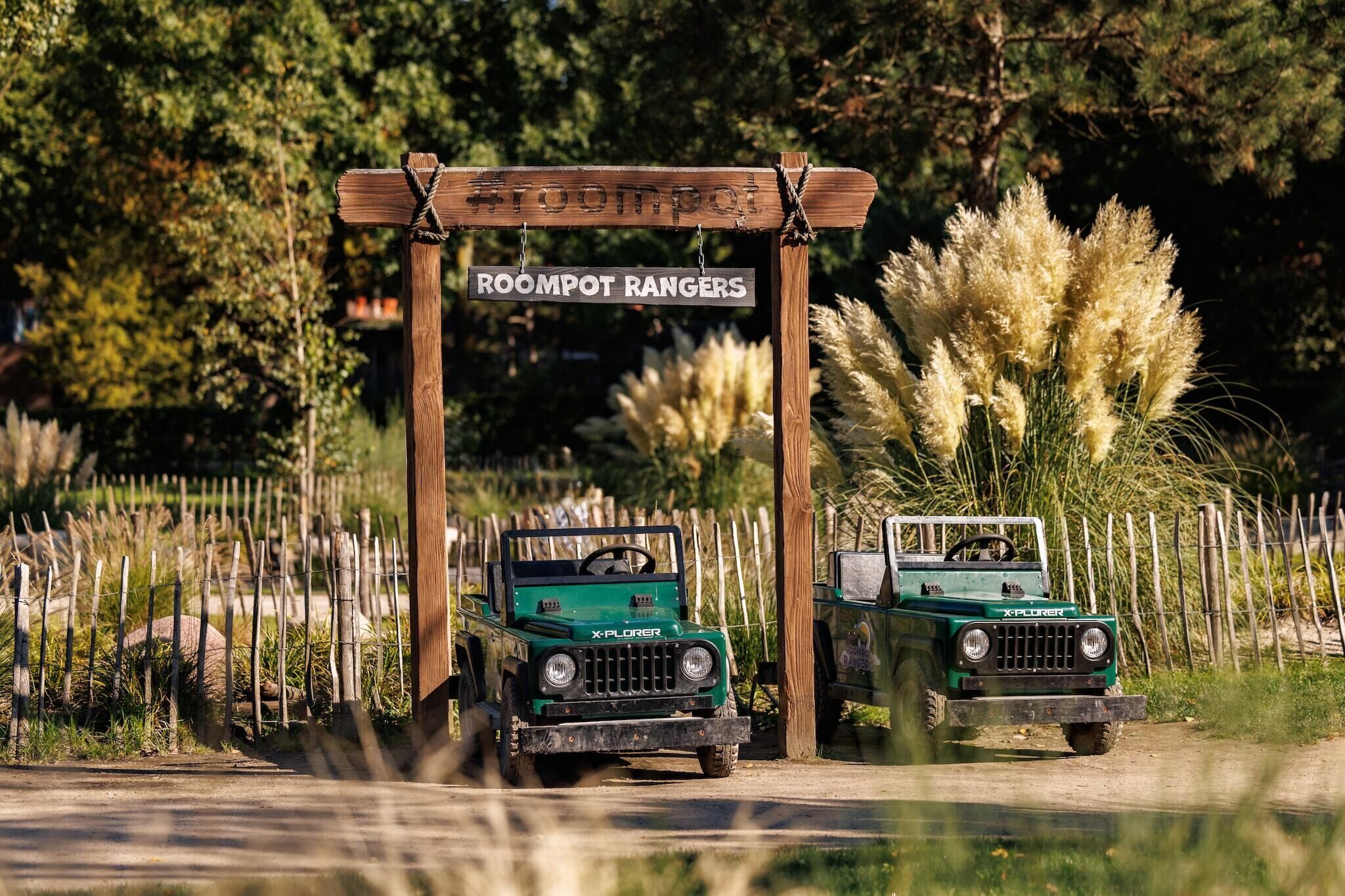 Two green off-road vehicles parked under a wooden archway with the text "ROOMPOT RANGERS".