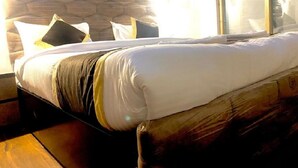 A bed with a wooden headboard, white bedding, and multiple pillows.
