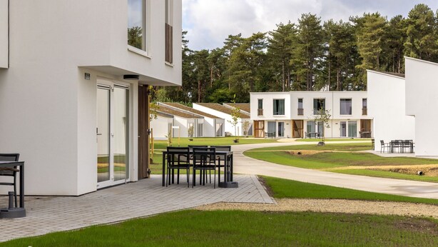Un edificio moderno con un patio attrezzato con tavolo e sedie.