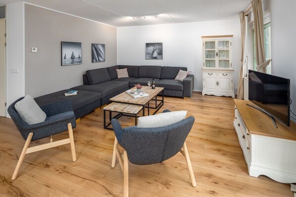 A modern living room with a sectional sofa, a small coffee table, and a white cabinet. - Villa in Banjaard near North Sea Beach (Kamperland)